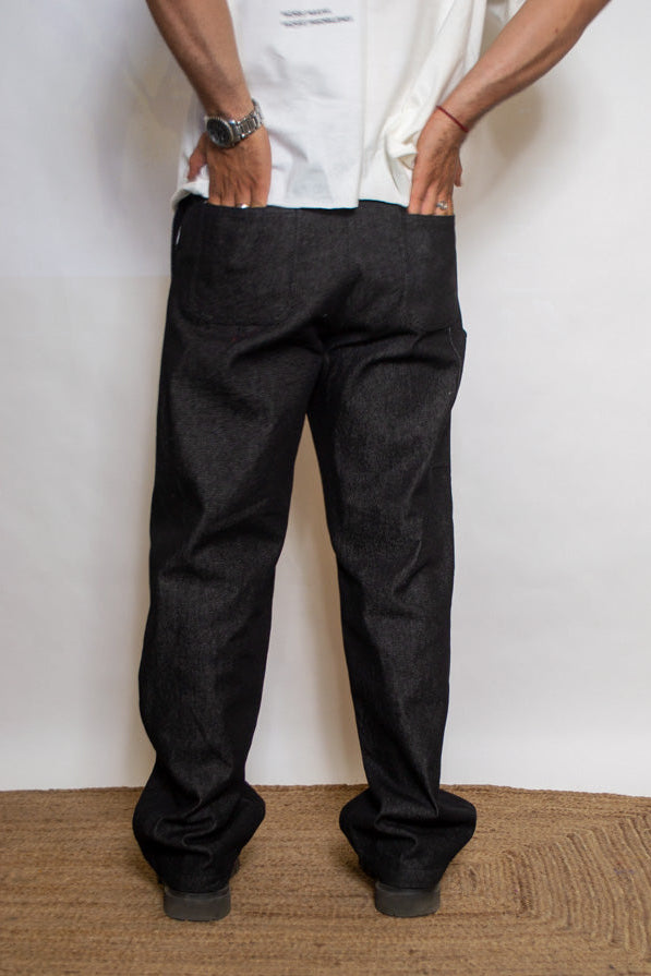 Person wearing black pants standing on a doormat with a white wall background
