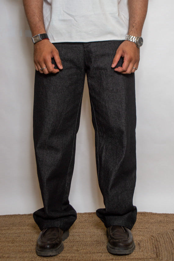 Person wearing dark jeans and a white shirt against a plain background