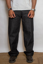 Person wearing dark jeans and a white shirt against a plain background